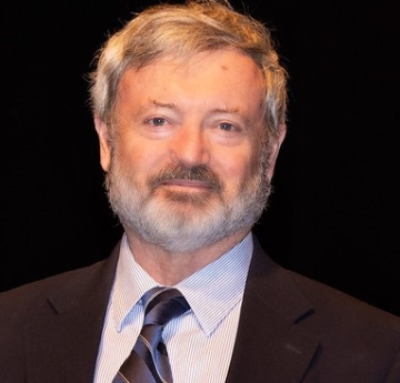 Caucasian male with grey hair and beard, wearing a suit and tie