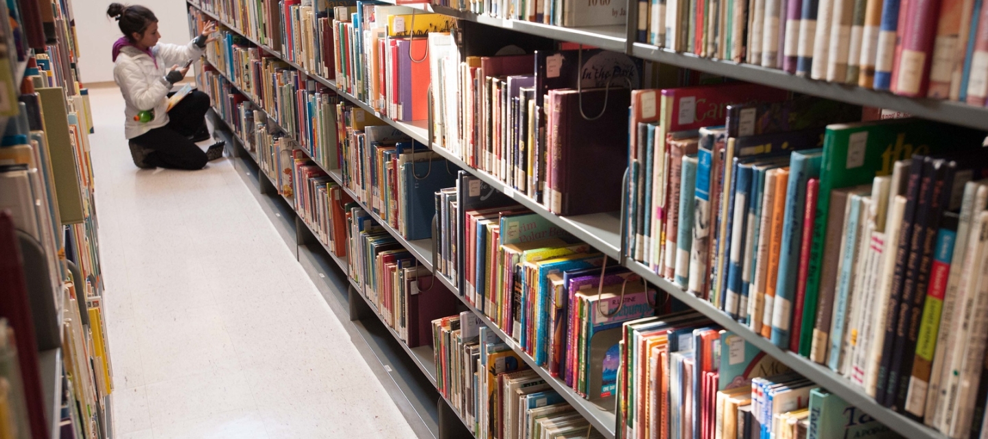 student searching for a book in the library stacks